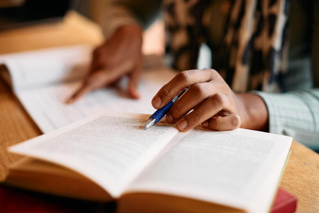 Close-up of female student learning from books in a library.